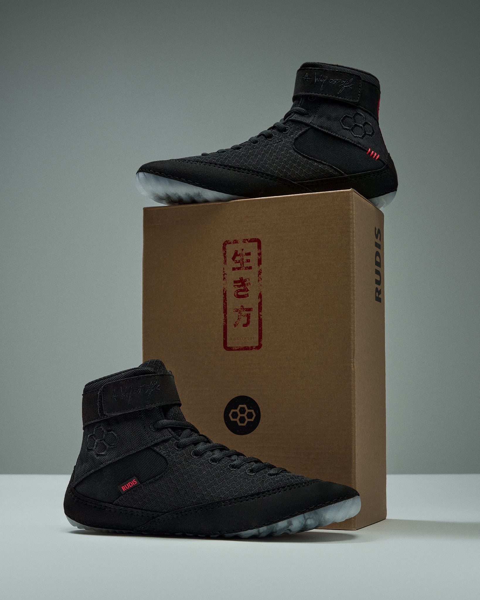 RUDIS Samurai Speed Adult Wrestling Shoes in Wabi-Sabi black with red accents, displayed on and beside a RUDIS shoebox with Japanese-inspired graphics.