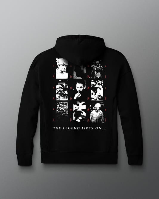 Back view of a black hoodie featuring a grid of grayscale and red-accented photo portraits depicting various moments in a wrestler's life and career of Dave Schultz. Beneath the collage, bold white text reads: “THE LEGEND LIVES ON...”