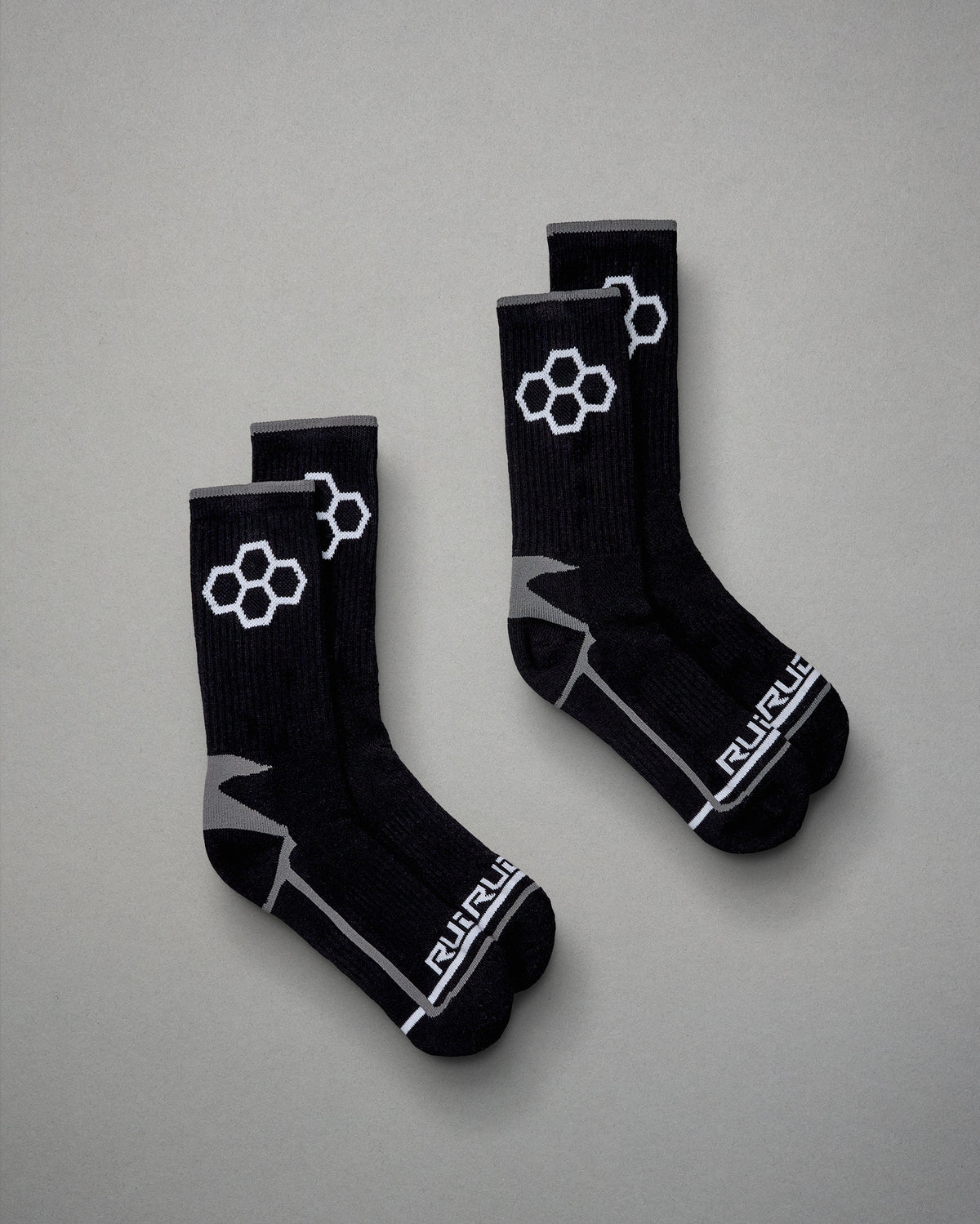A pair of black athletic socks featuring a geometric design and branding on a gray background