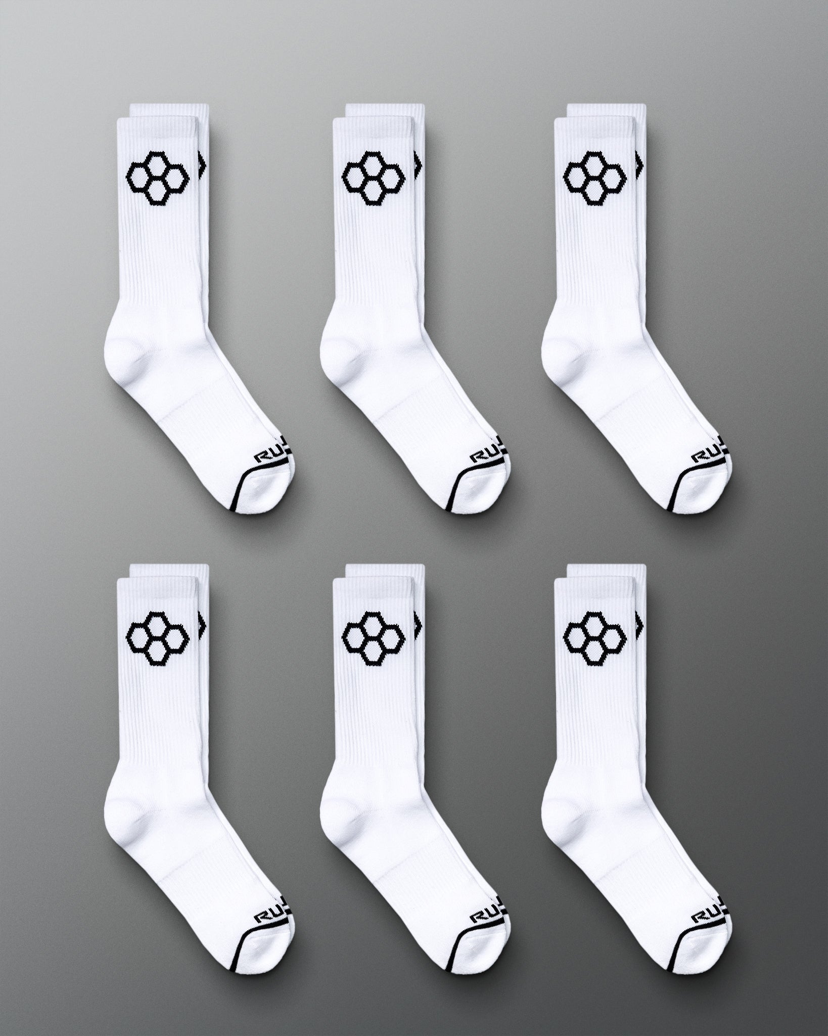 This image displays six pairs of white sports socks featuring a distinctive black hexagonal logo on the sides and black accents on the toes