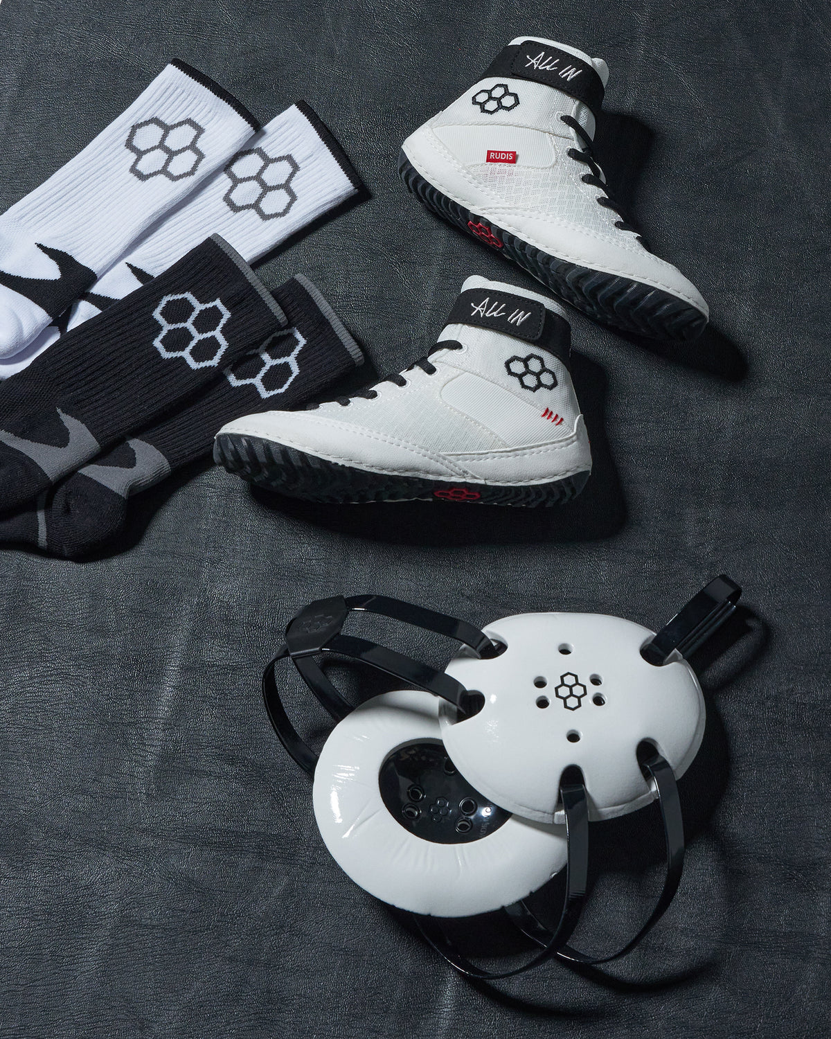 White wrestling with black and red accents, accompanied by matching socks and a white headgear on a dark surface.
