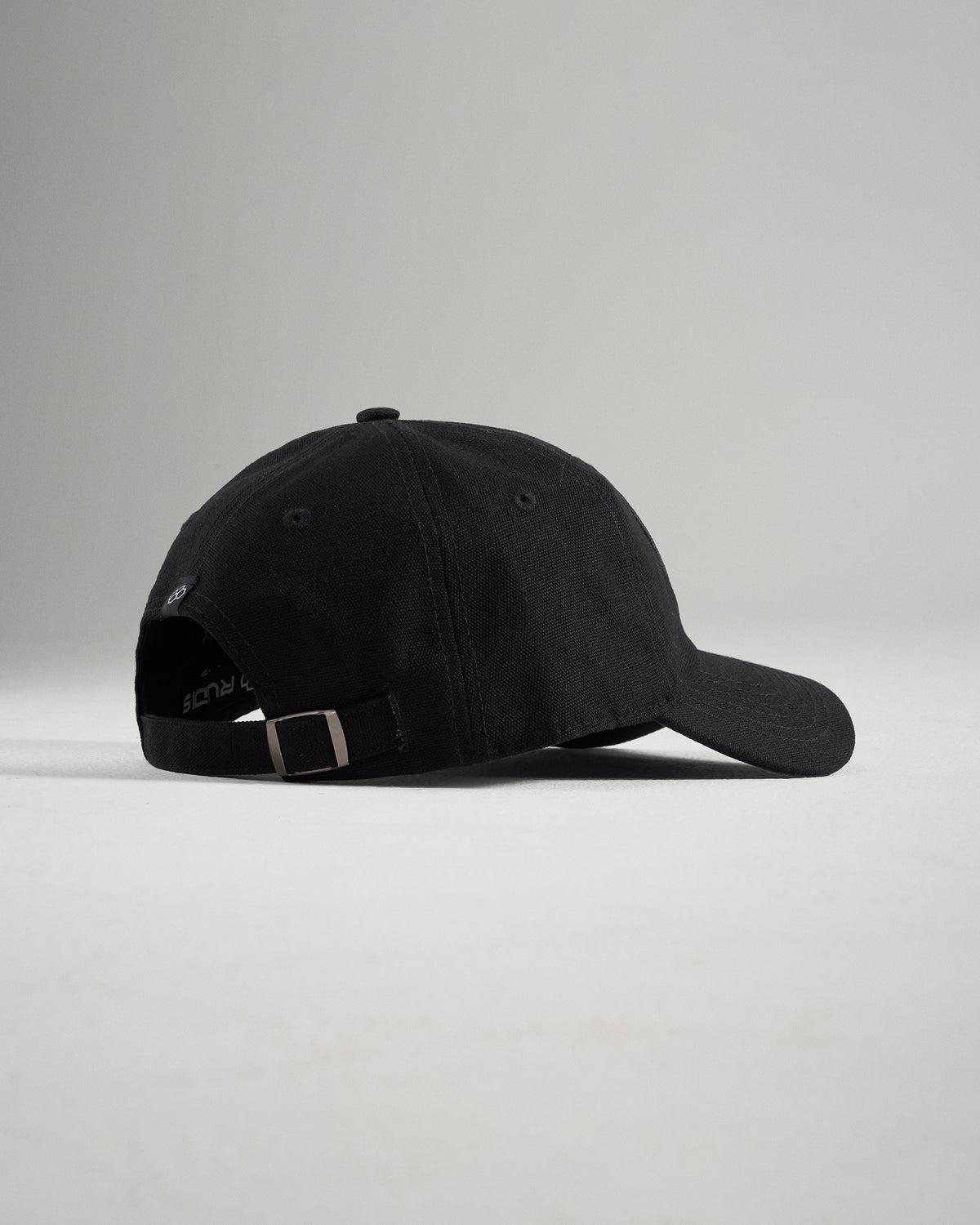 A simple black baseball cap viewed from the side showcasing its curved brim and adjustable strap at the back