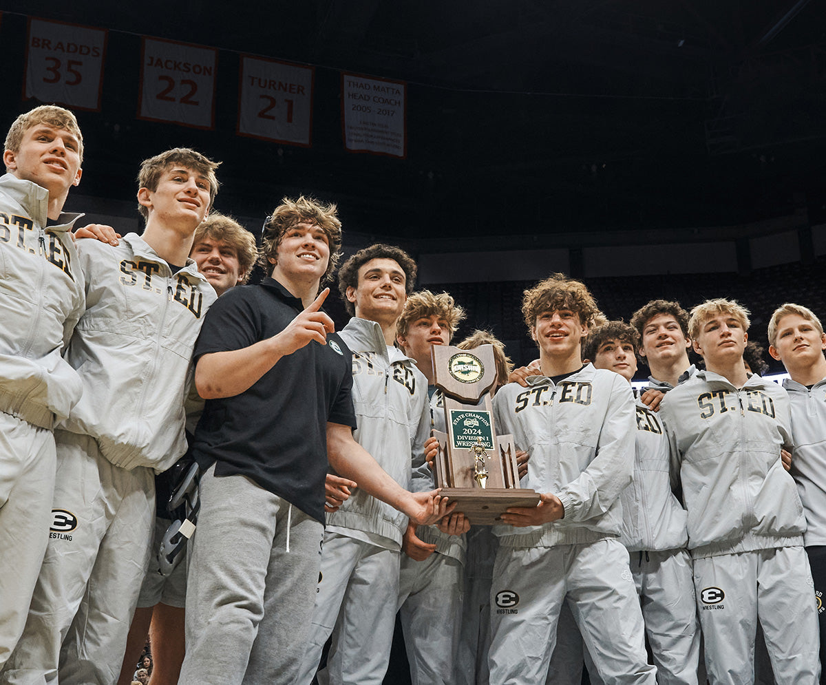 Group of young men in custom team sports uniforms holding a trophy indoors. Wearing RUDIS custom team gear