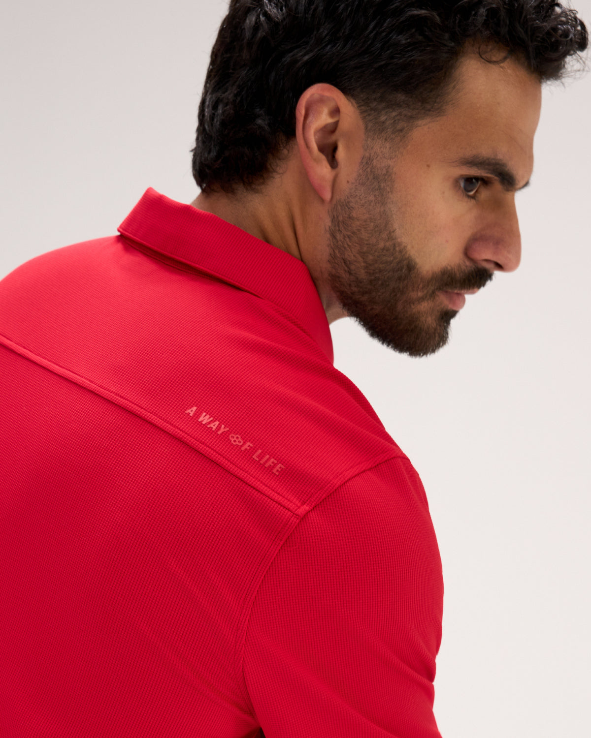 Close-up of the RUDIS Go-To Polo in Red, highlighting the textured fabric, structured collar, shoulder seam construction, and subtle A Way of Life branding across the upper back.