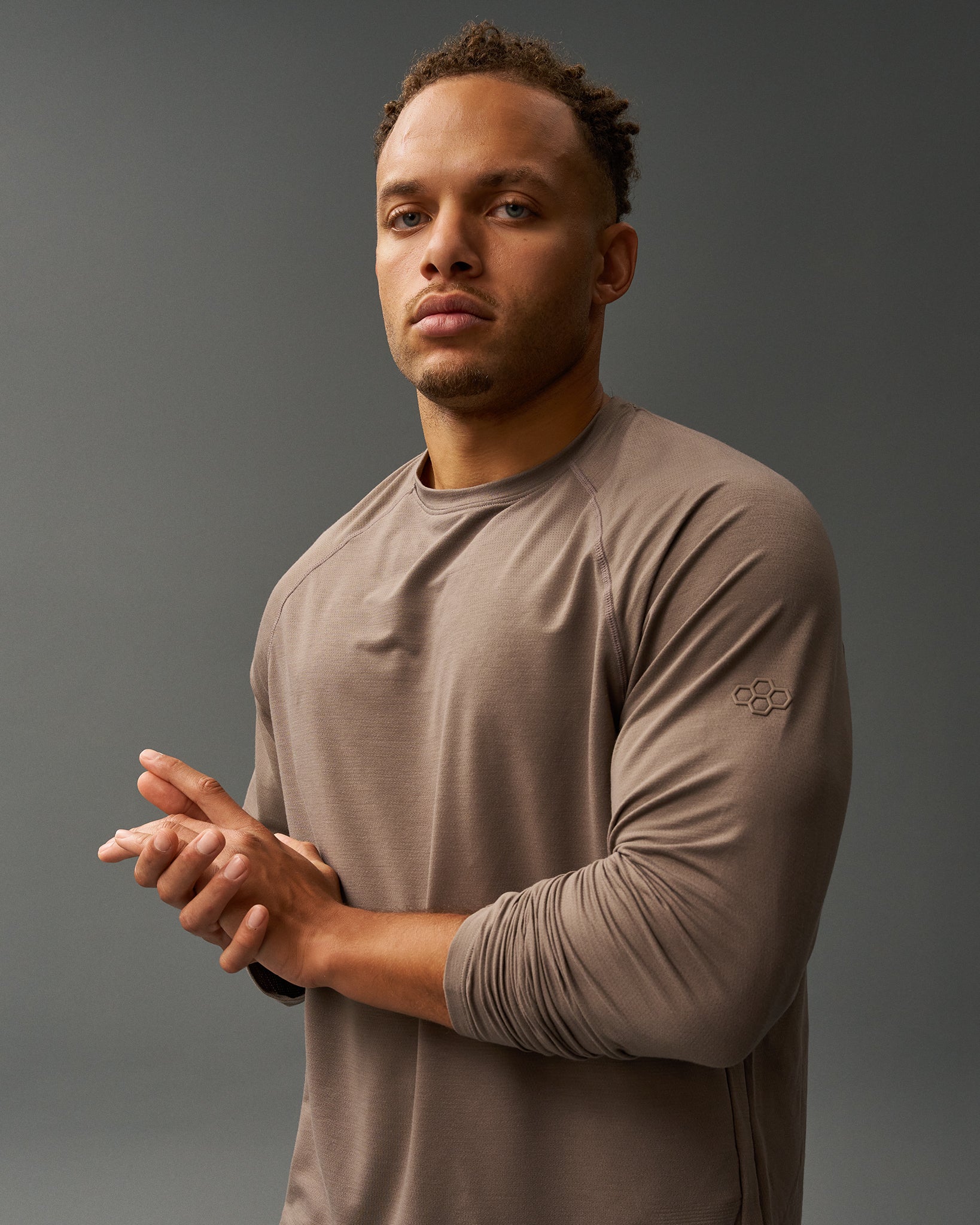 Man wearing a brown long-sleeve shirt against a gray background