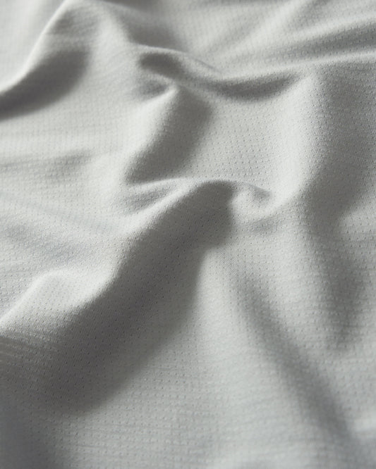 Light gray textured fabric with a dotted pattern shows subtle folds and a soft surface suitable for clothing or upholstery.