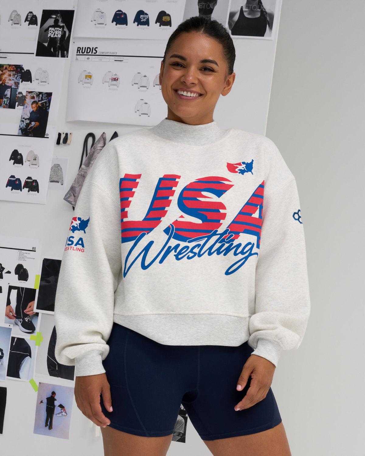Female model wearing the RUDIS USA Wrestling Comfort Fleece Mockneck sweatshirt in Heather Silver with oversized red and blue USA Wrestling graphics