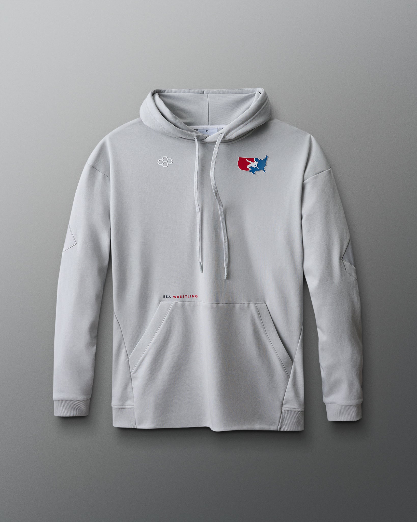 A light gray pullover hoodie displayed against a red-to-blue gradient background. The hoodie features a front kangaroo pocket, ribbed cuffs, and a drawstring hood. On the upper left chest, there's a small white hexagonal RUDIS logo. On the right chest, a red, white, and blue USA Wrestling logo shows a wrestler in action over a map of the United States. Below the pocket, centered on the lower torso, is small text reading "USA WRESTLING" in black and red font.