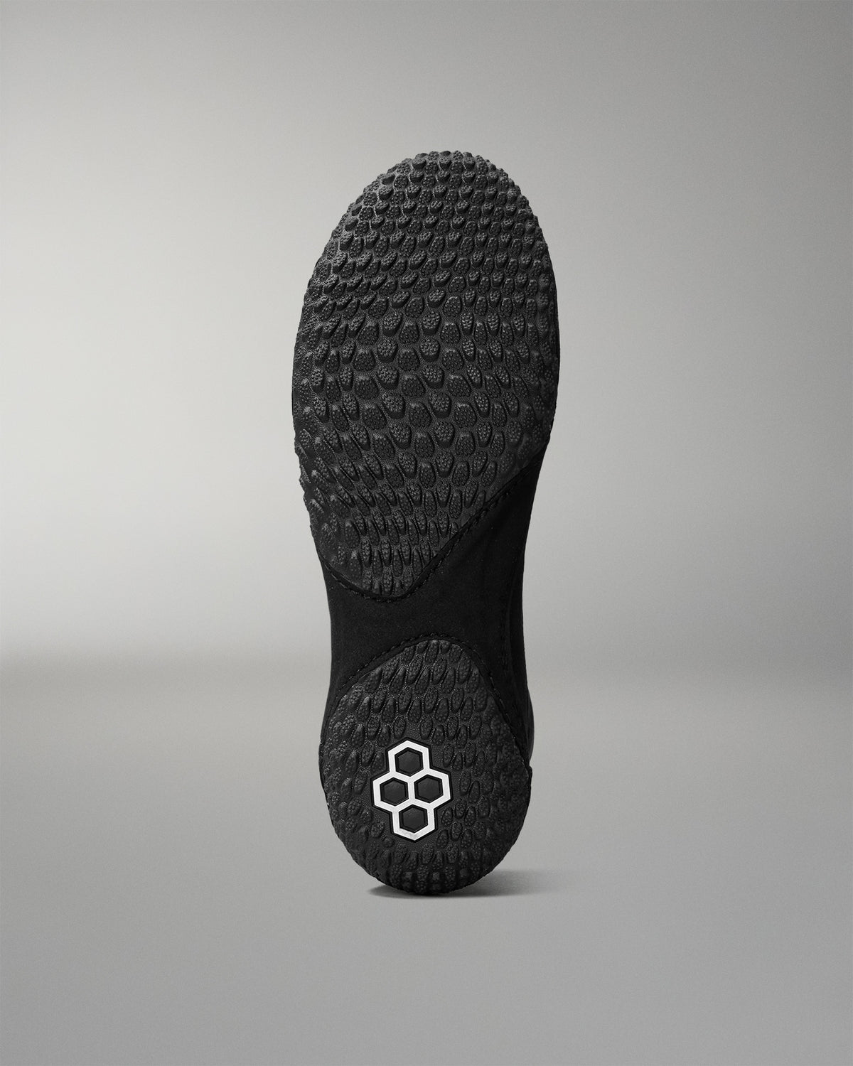Black sole of a wrestling shoe with a brand logo on a gray background
