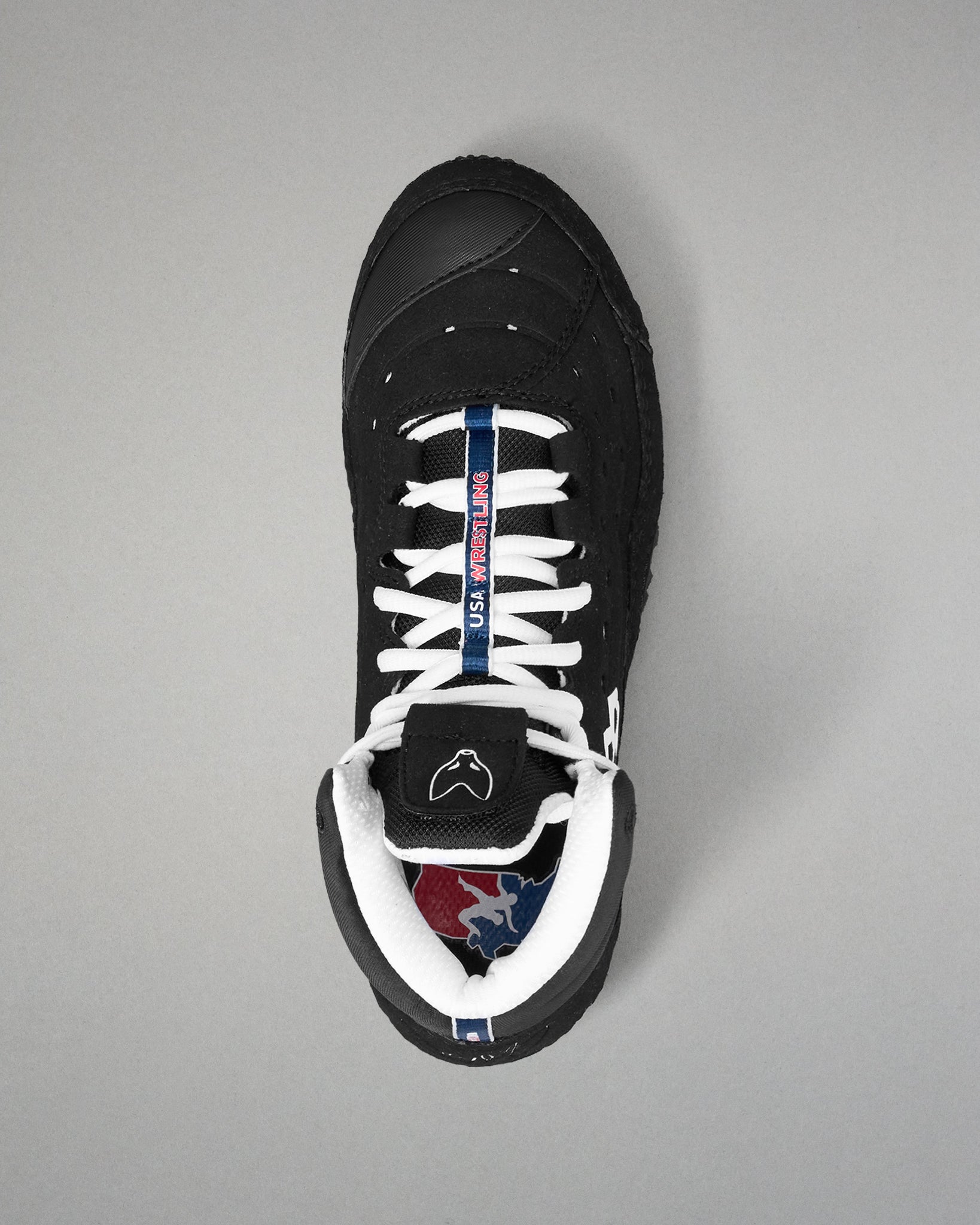 Black wrestling shoe with white laces on a gray background