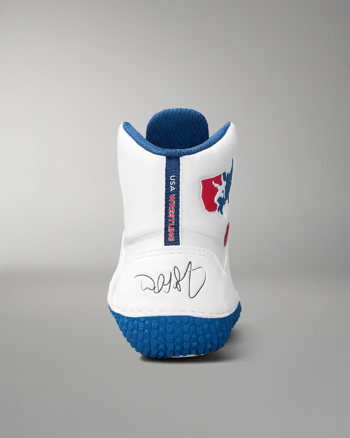 White wrestling shoe with blue sole and red and blue logo on a gray background