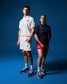 A male and a female wrestler standing side by side wearing USA Wrestling polos in white and blue colors, with the male in the foreground and the female in the background.