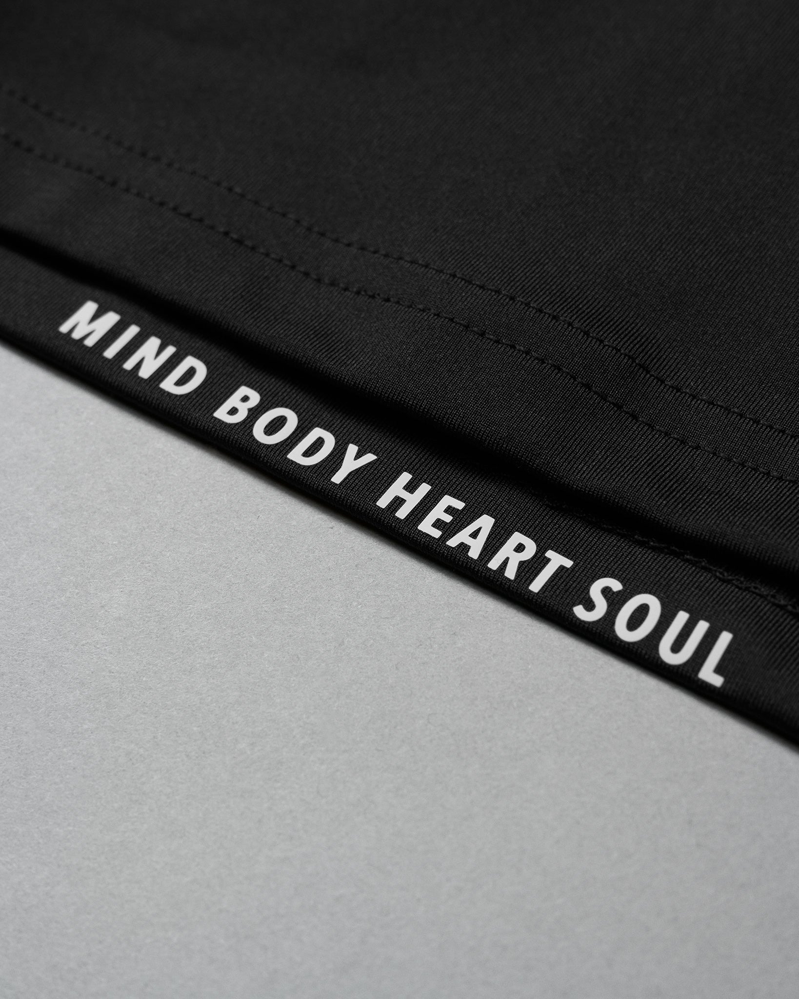 Black waistband with 'MIND BODY HEART SOUL' text on a gray background