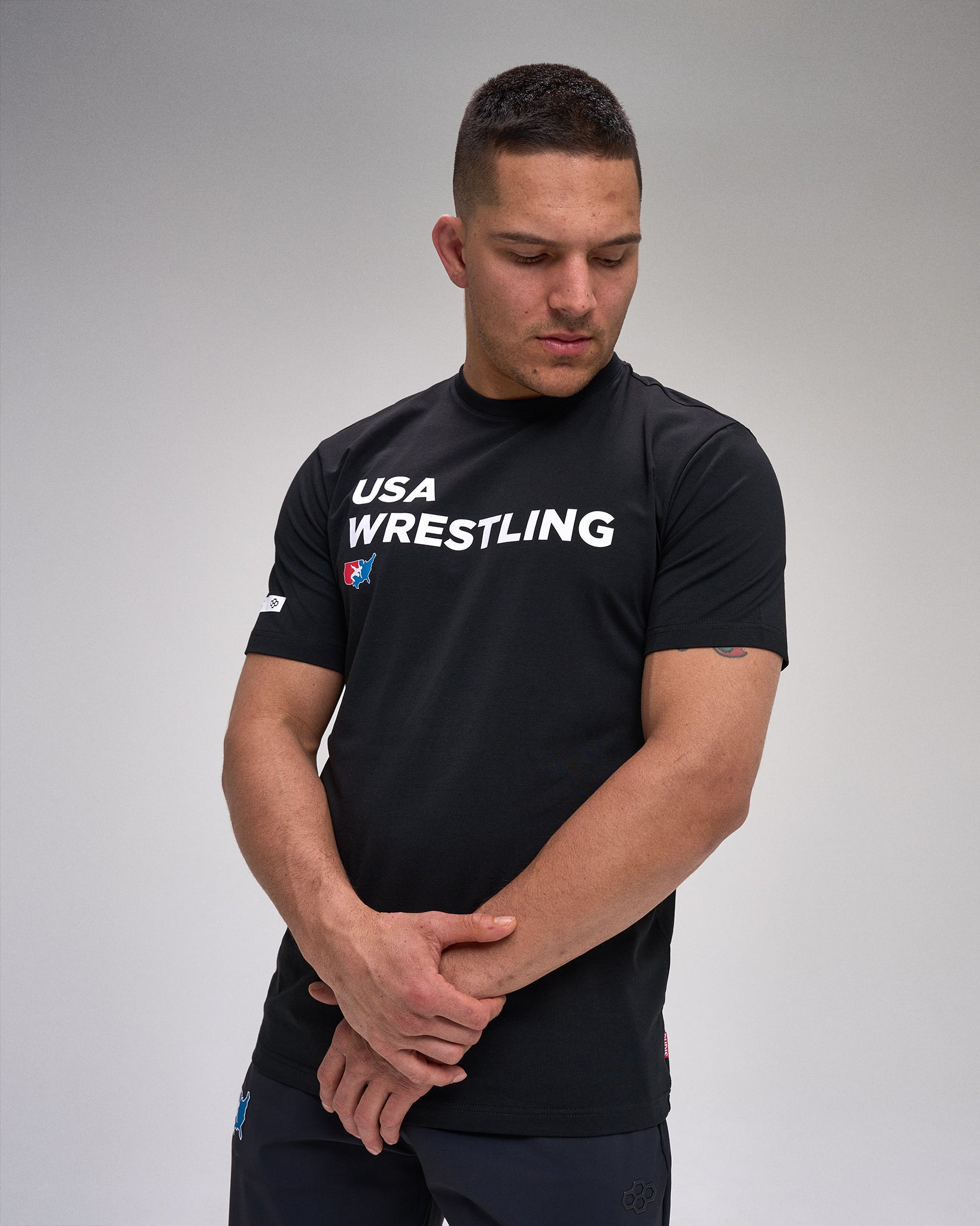 Man wearing a black USA Wrestling shirt on a gray background