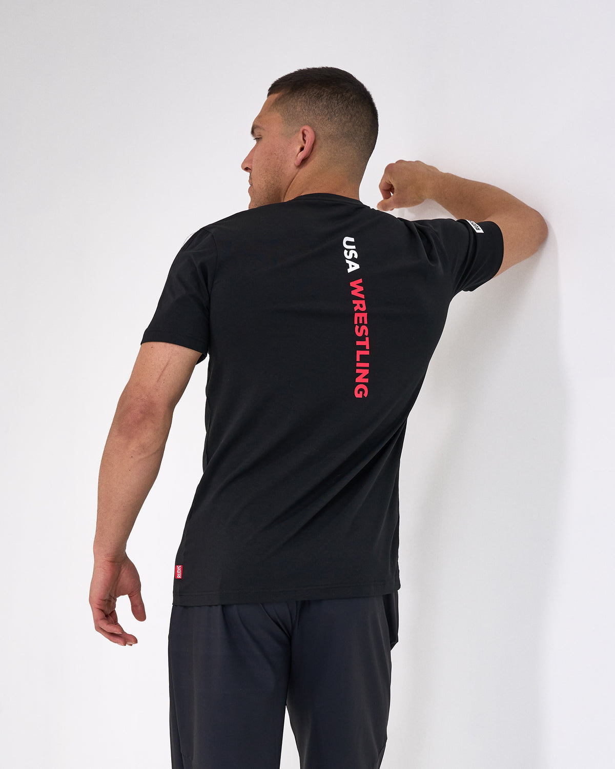 Person wearing a black 'USA Wrestling' t-shirt against a white background