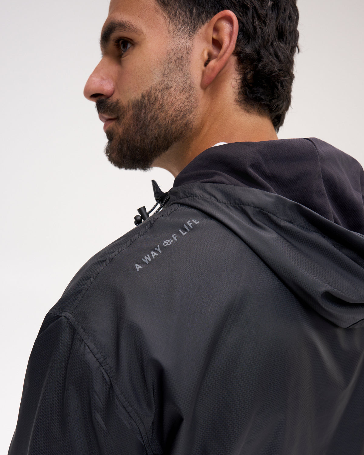 Close-up of the RUDIS Motion Windbreaker in Black, highlighting the textured fabric, hood construction, and signature RUDIS A Way of Life branding along the upper shoulder.
