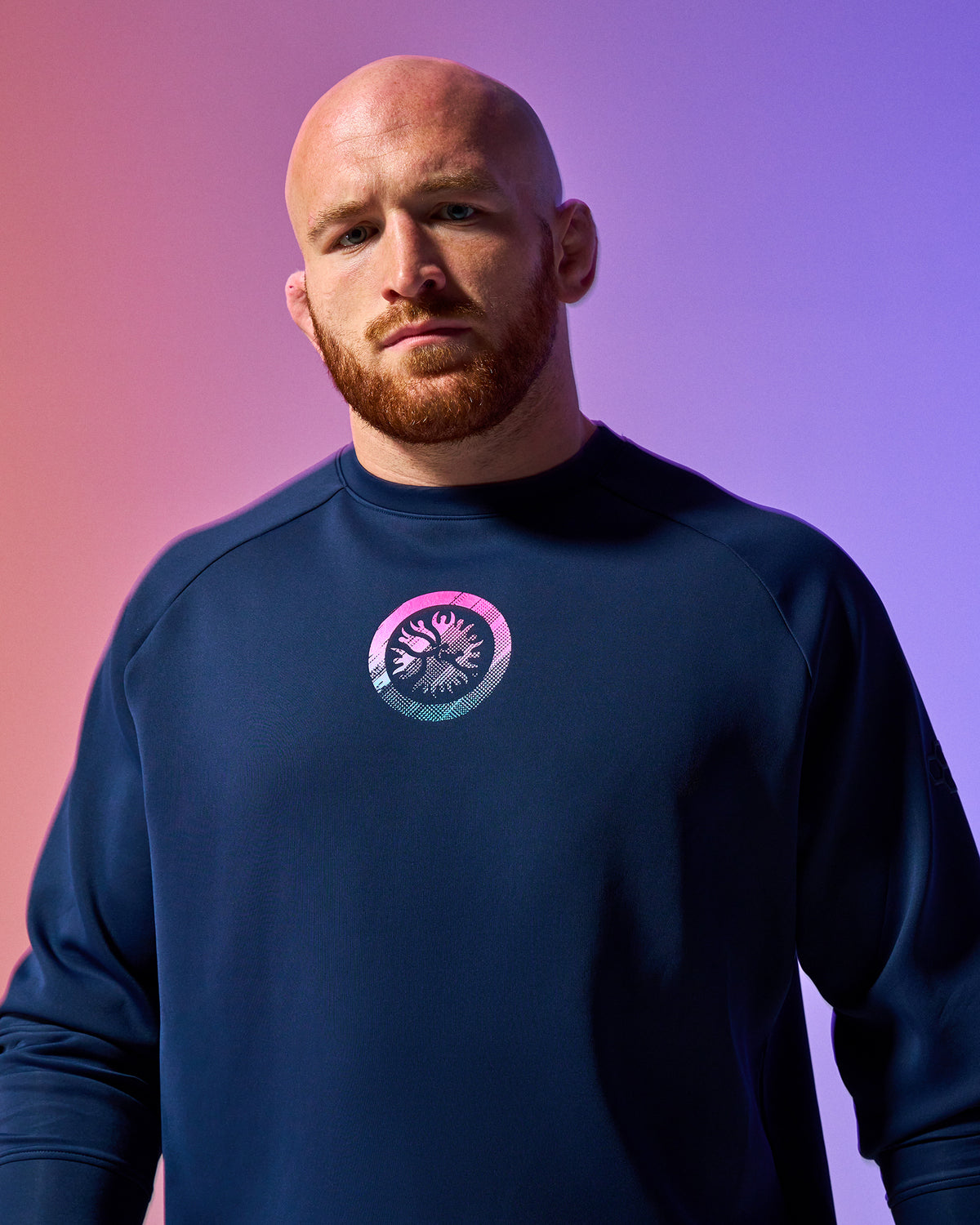 Man wearing a blue sweatshirt with a logo on a gradient background