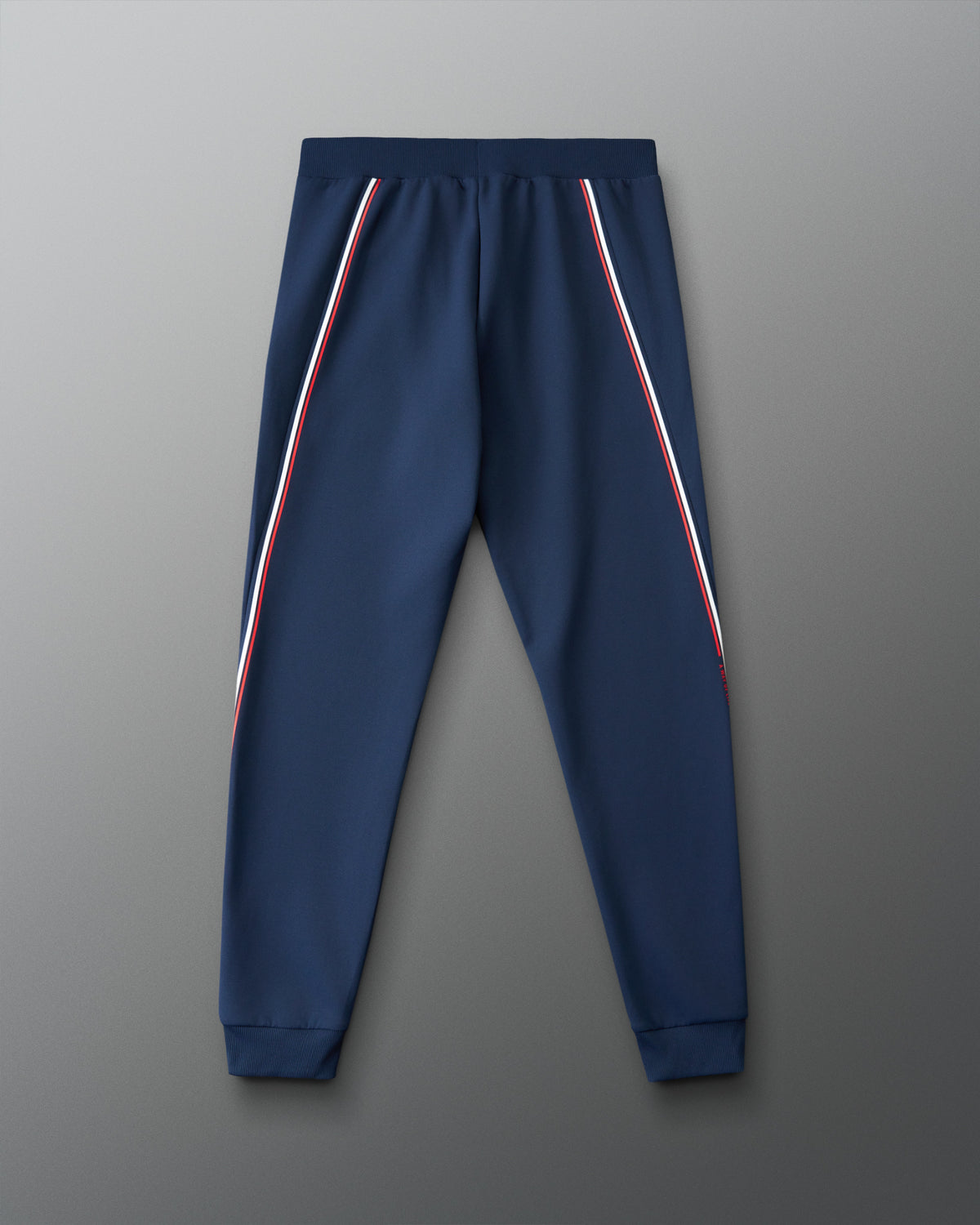 Navy blue jogger pants with red and white stripes on a gray background