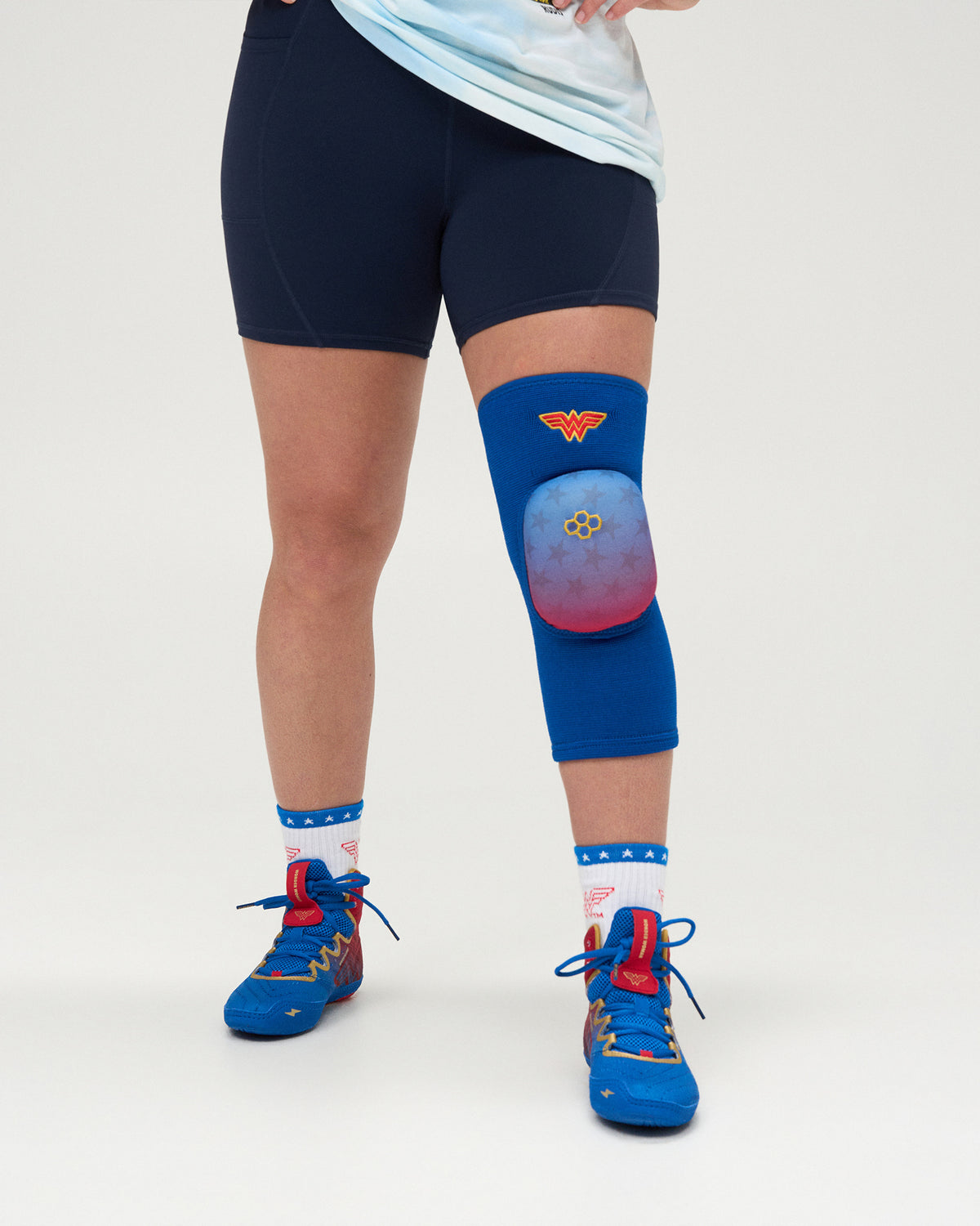 RUDIS Wonder Woman Cushion Wrestling Knee Pad worn by an athlete, featuring a royal blue sleeve, star-patterned cushion and Wonder Woman emblem.