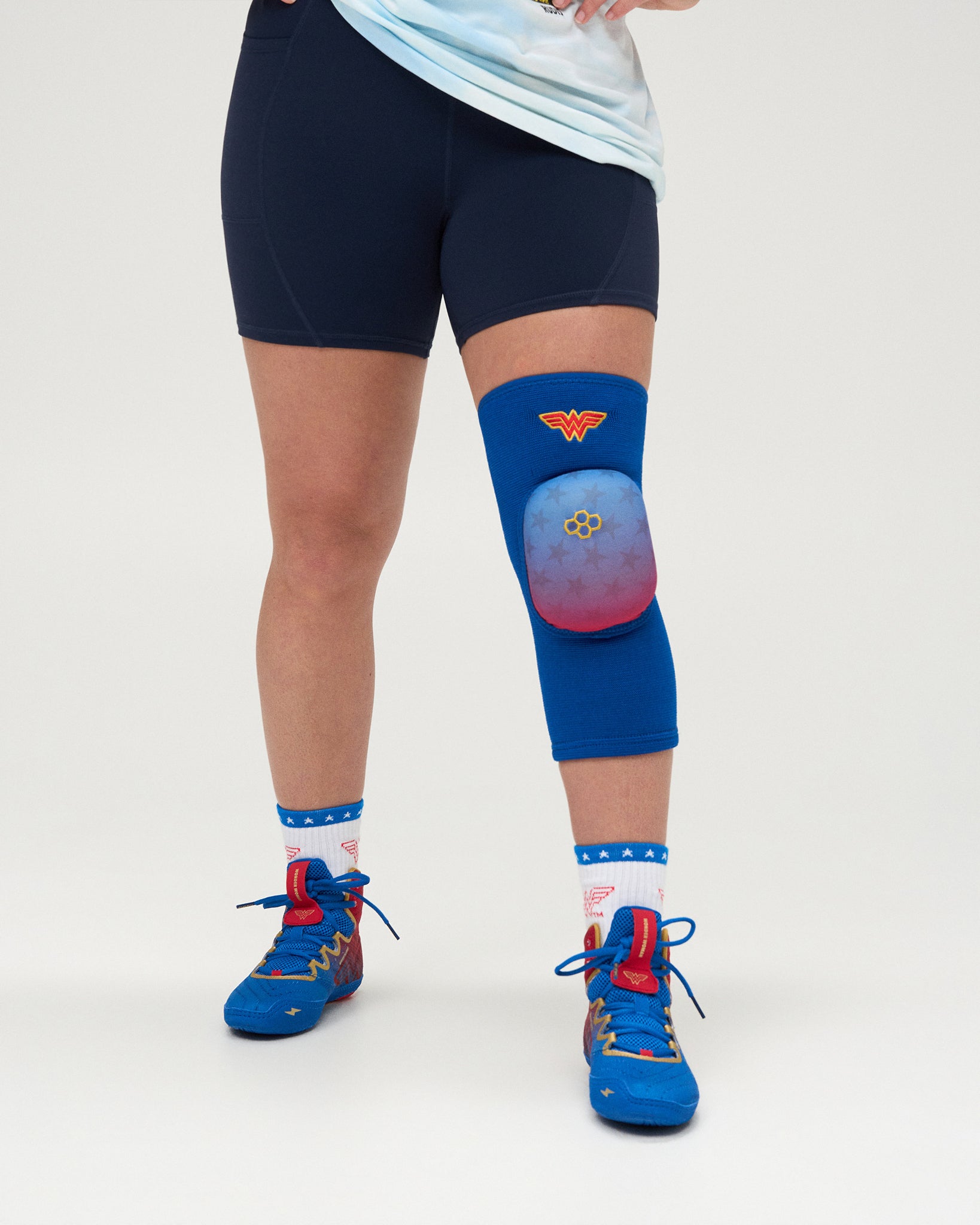RUDIS Wonder Woman Cushion Wrestling Knee Pad worn by an athlete, featuring a royal blue sleeve, star-patterned cushion and Wonder Woman emblem.