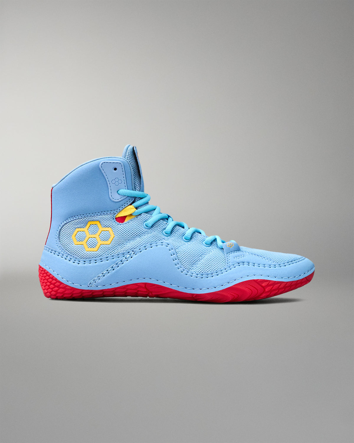 Side profile of RUDIS JB1 Superman wrestling shoe showing light blue mesh upper, yellow RUDIS logo and red traction outsole.