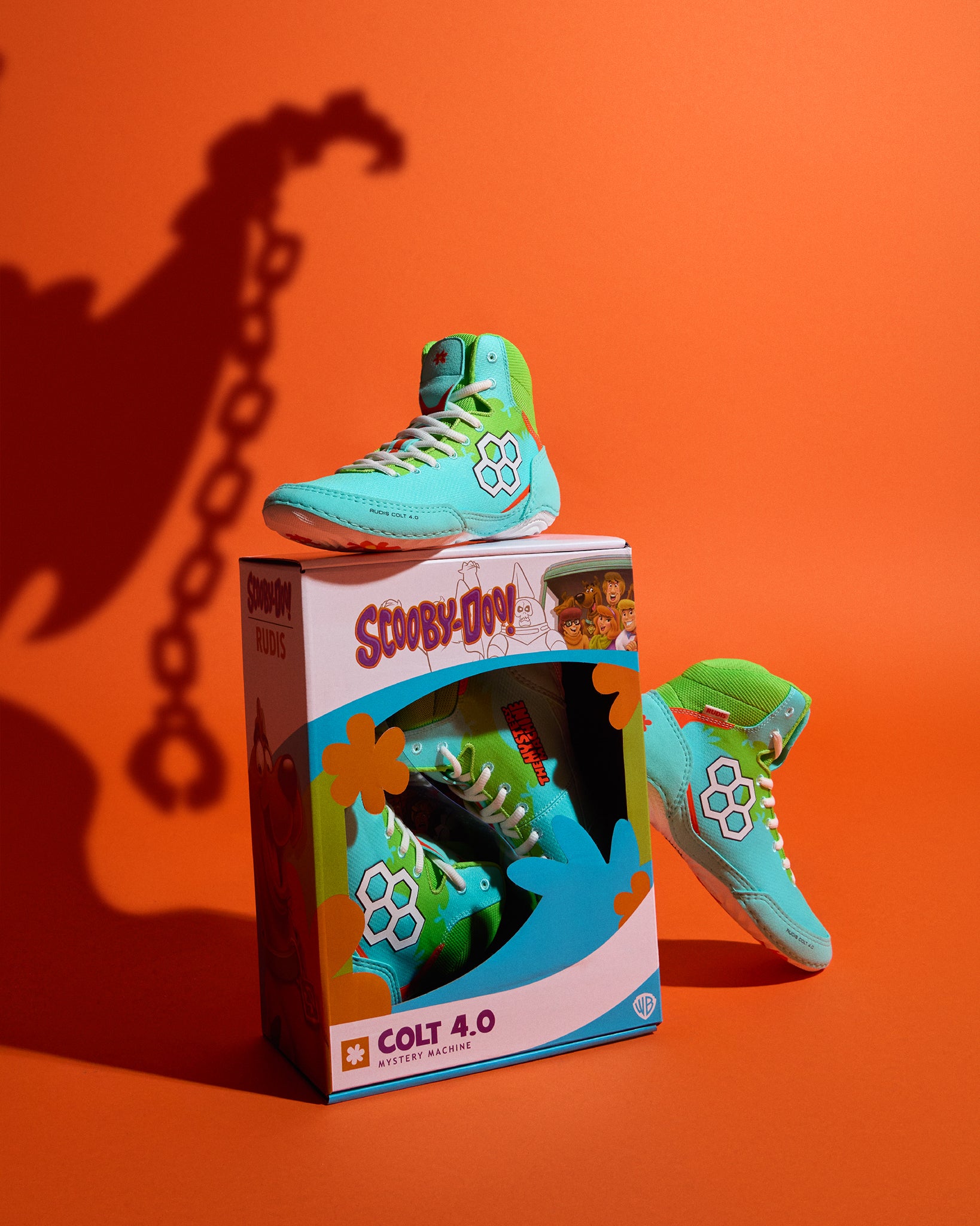 RUDIS Scooby-Doo Colt 4.0 adult wrestling shoes in Mystery Machine turquoise and green colorway displayed with custom Scooby-Doo packaging against an orange background.