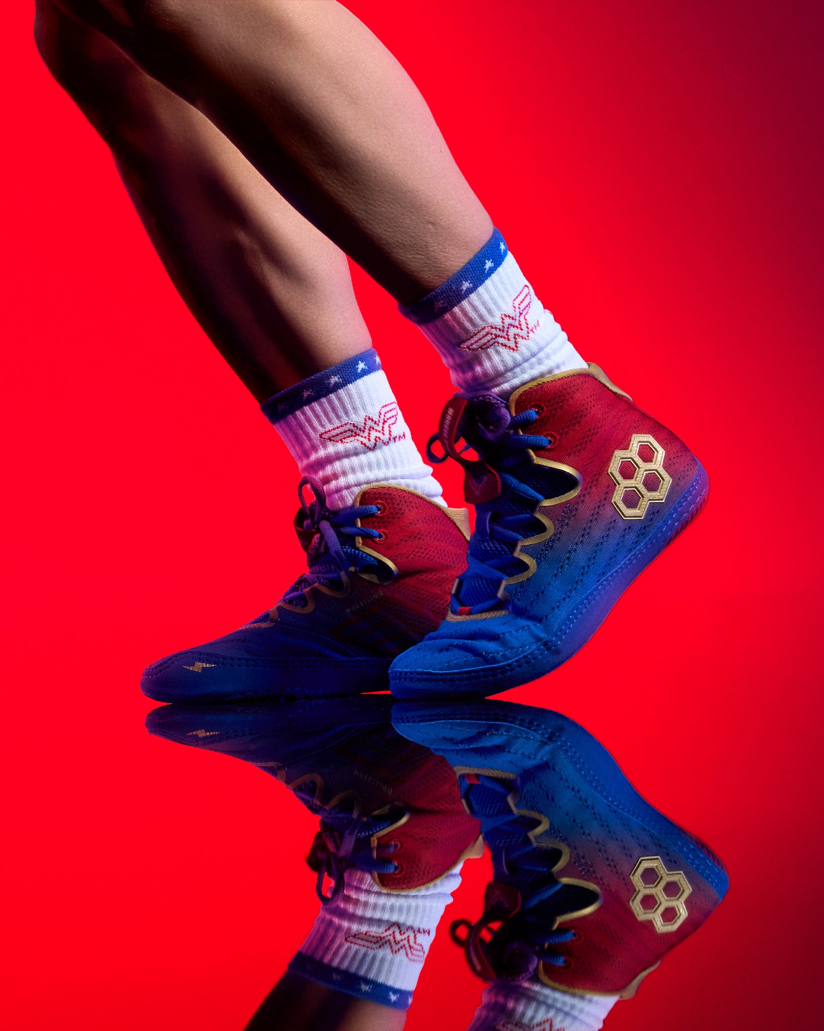 RUDIS Wonder Woman Hildebrandt 2.0 women's wrestling shoes worn with Wonder Woman socks, featuring red and blue uppers, gold accents and a reflective red background.