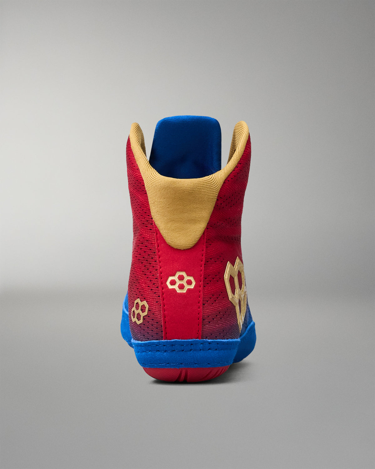 Rear view of RUDIS Wonder Woman Hildebrandt 2.0 women's wrestling shoe, showing the red heel, gold collar lining, RUDIS branding and blue sole.