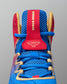 Close-up of RUDIS Wonder Woman Hildebrandt 2.0 women's wrestling shoe, highlighting blue mesh, gold lace detailing and red tongue with Wonder Woman emblem.