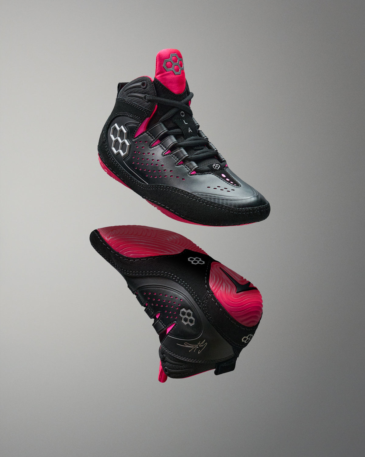 Black and pink wrestling shoes on a gray background