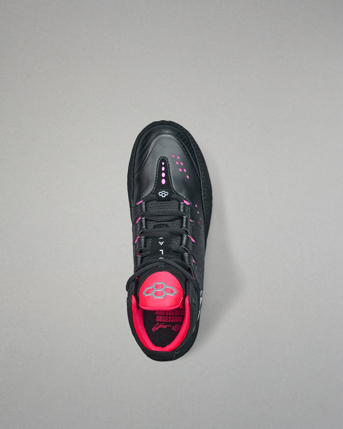 Black and pink wrestling shoe on a gray background