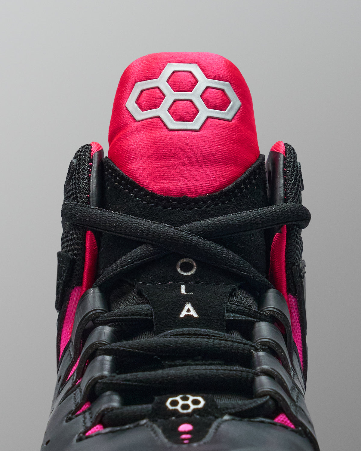 Black and pink wrestling shoe with a prominent brand logo on a gray background
