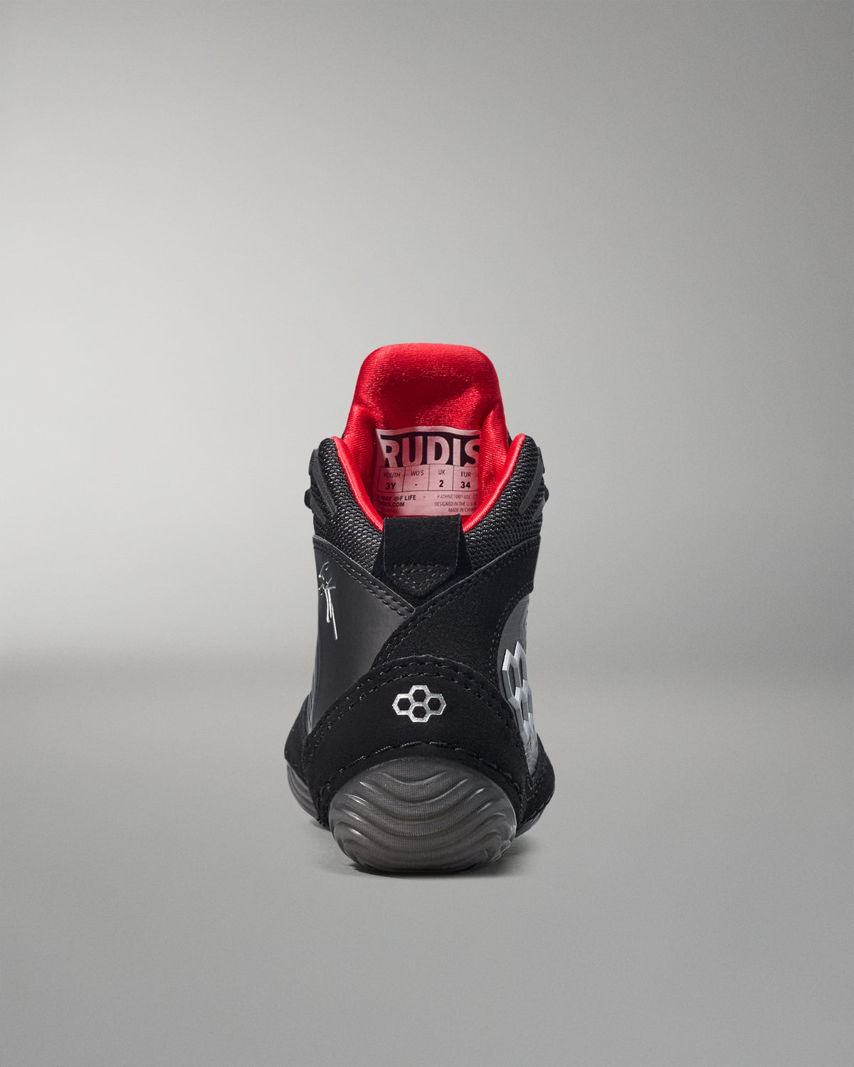 Black wrestling shoe with red lining on a gray background