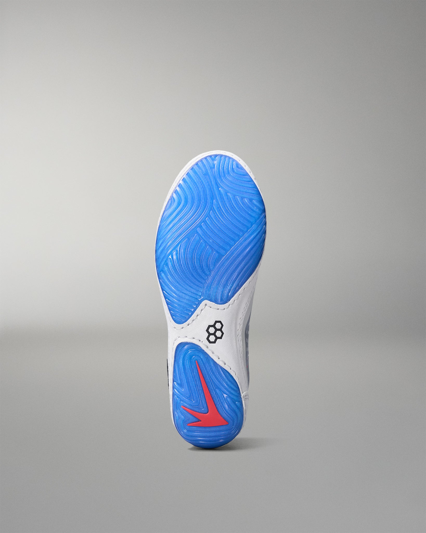 Sole of a wrestling shoe with blue outsole and red logo on a gray background
