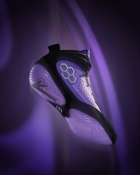 Black and white wrestling shoe with a glowing sole on a dark background