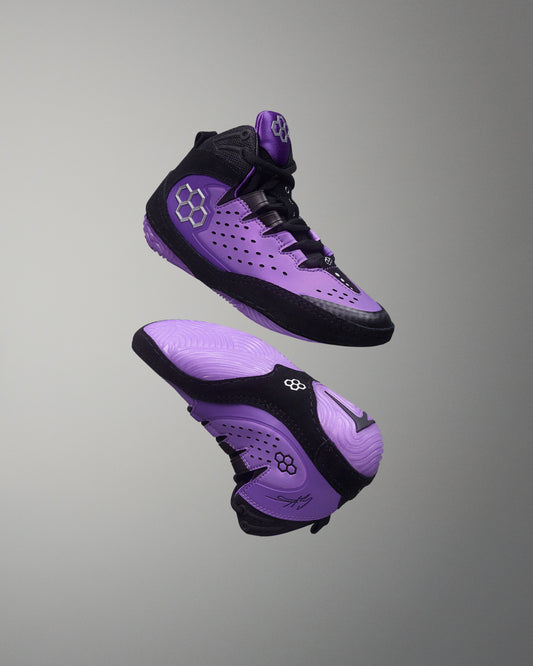 Purple and black wrestling shoes on a gray background