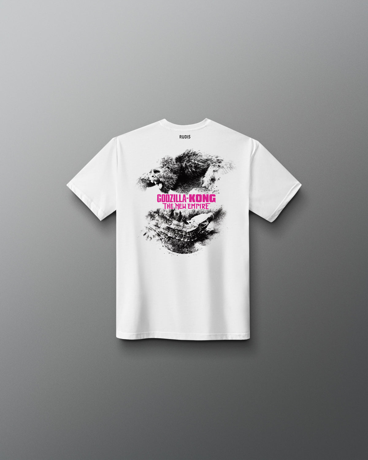 A white short-sleeve t-shirt shown from the back, featuring a black and gray splattered graphic with pink text reading 'Godzilla KONG' and smaller text below, displayed against a dark gray gradient background.