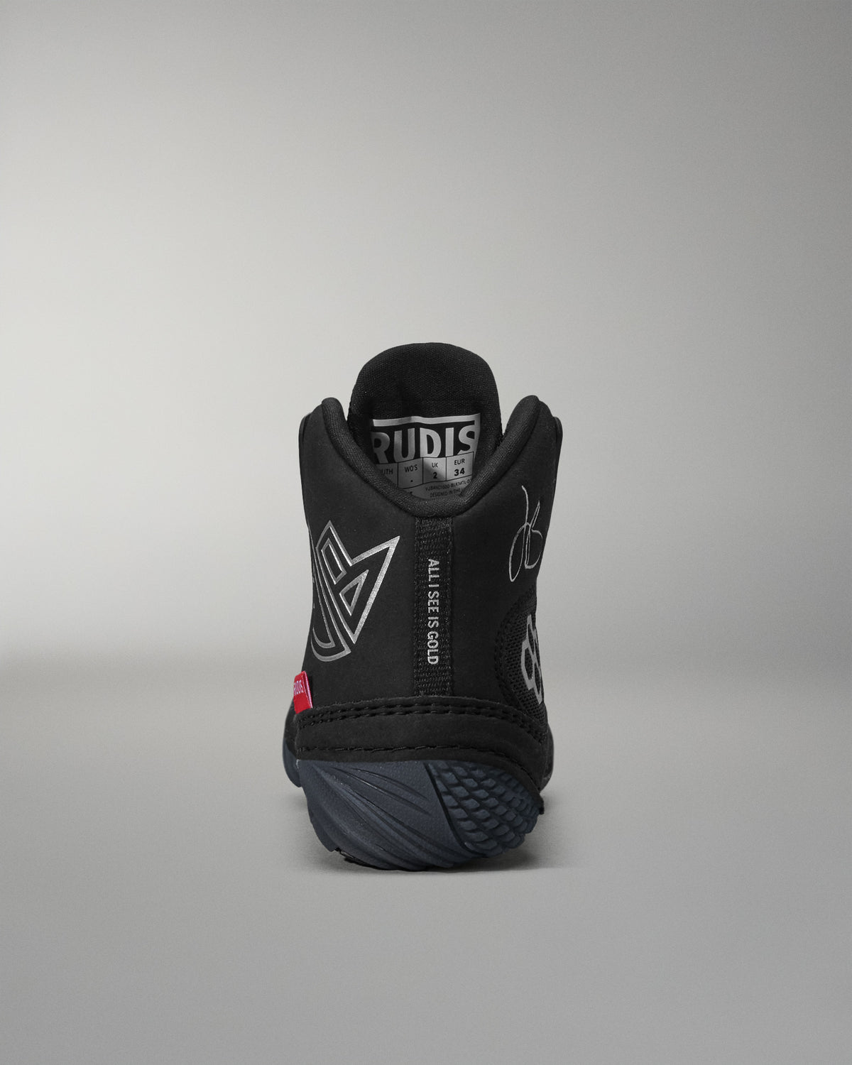 Black wrestling shoe with visible branding on a gray background