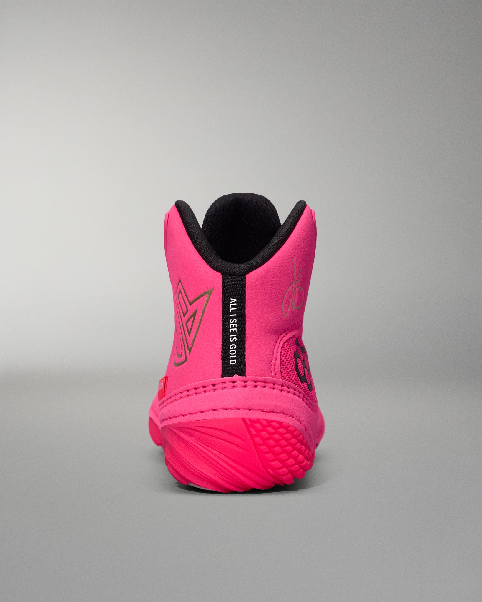 Pink wrestling shoe with black sole on a gray background