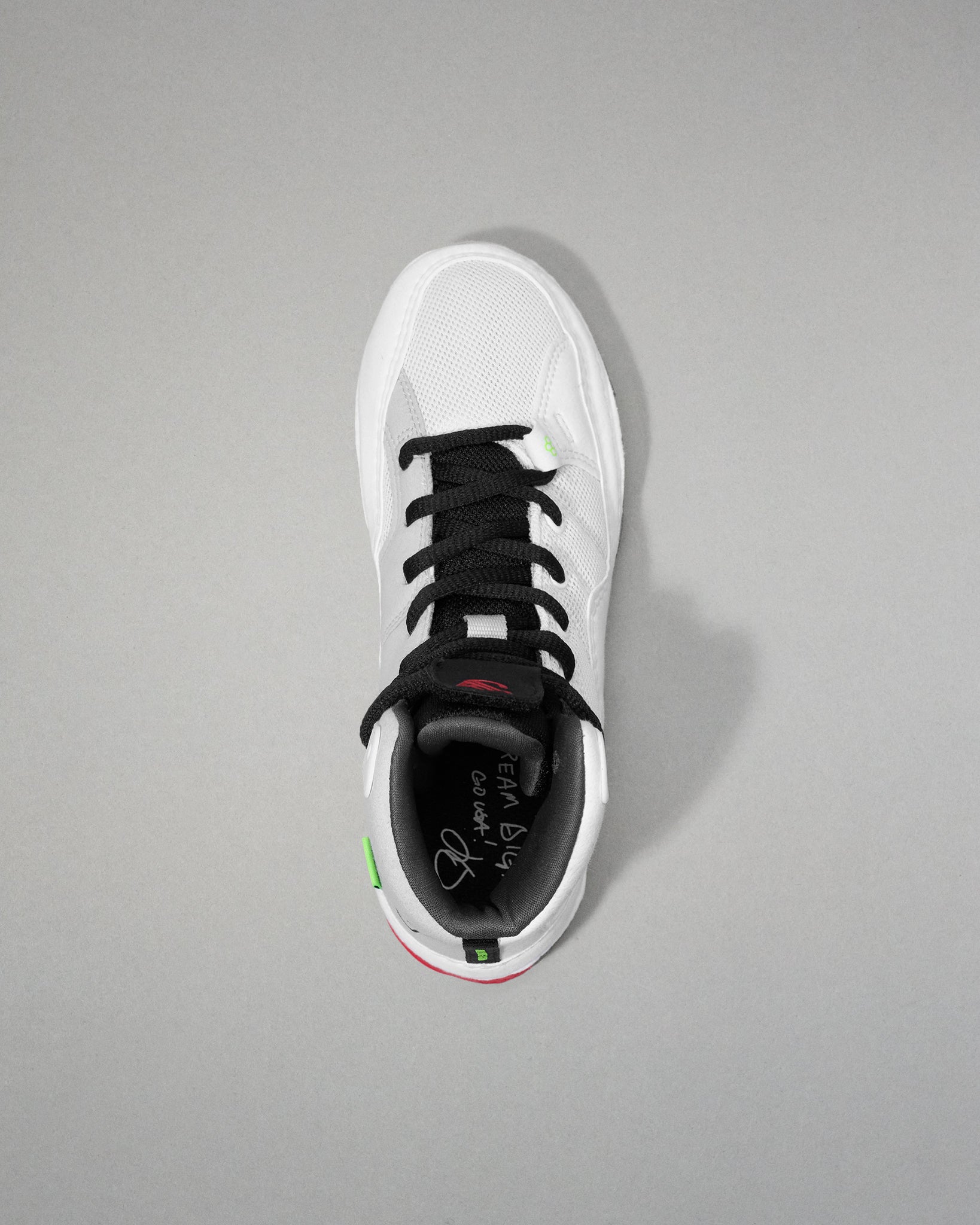 White wrestling shoe with black laces on a gray background