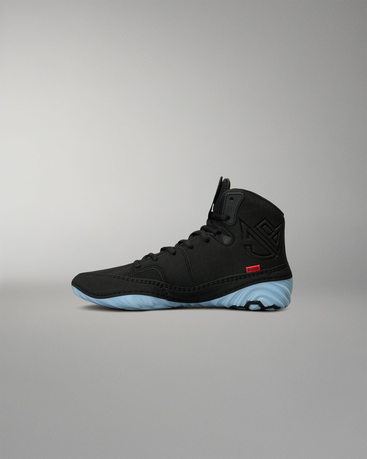 RUDIS JB1 Youth Wrestling Shoe in Dark Shark shown from the medial side, featuring the black high-top construction, tonal JB branding, red RUDIS accent, and light blue outsole.