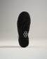 A close-up view of the textured black sole of a sneaker featuring a pink accent and a modern design