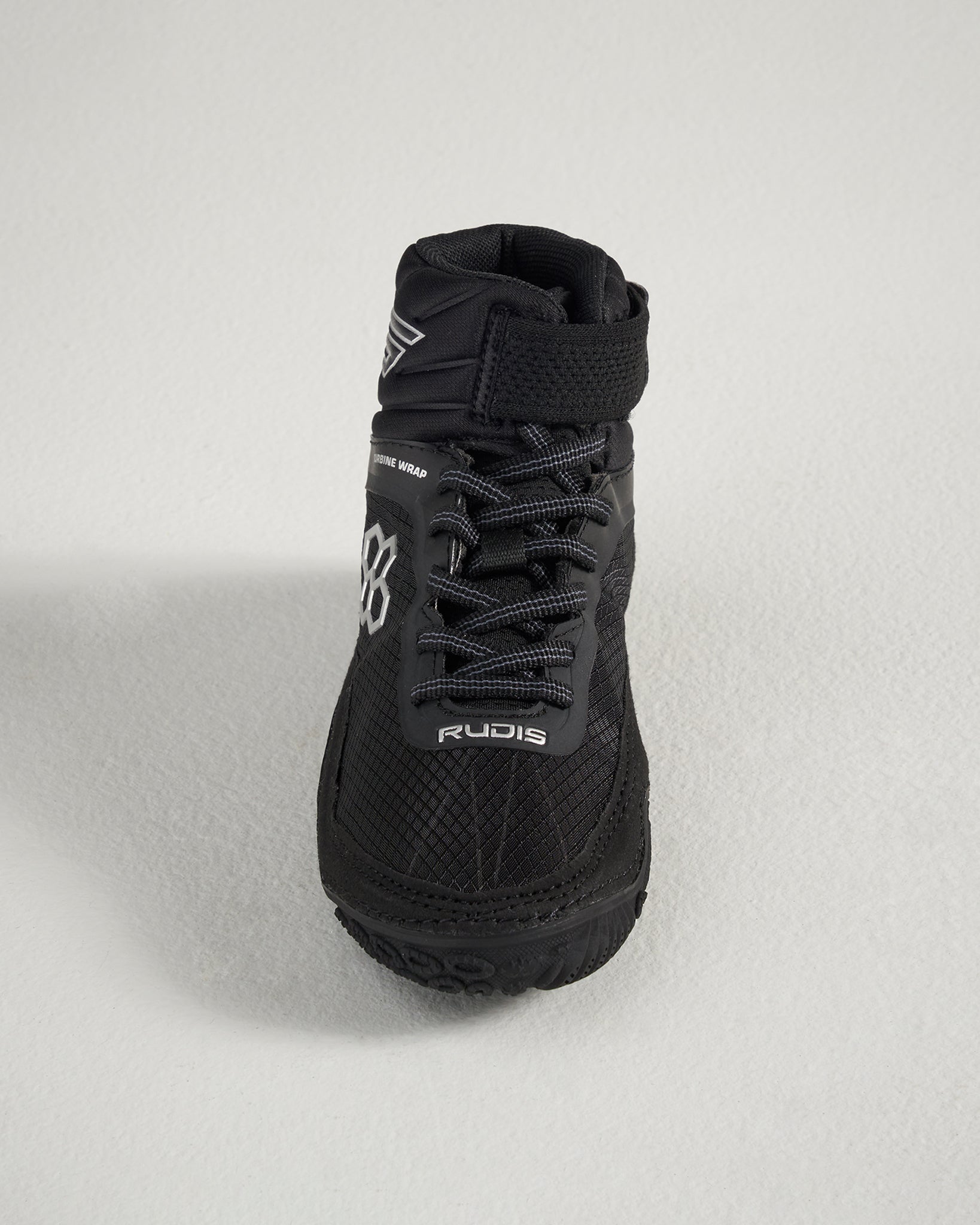 A top view of a sleek black wrestling shoe featuring intricate textures a high ankle support design and reflective branding