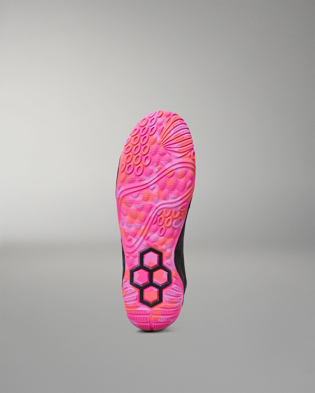 The outsole of a wrestling shoe in vibrant pink and orange with a black hexagonal logo, shown against a neutral gray background.