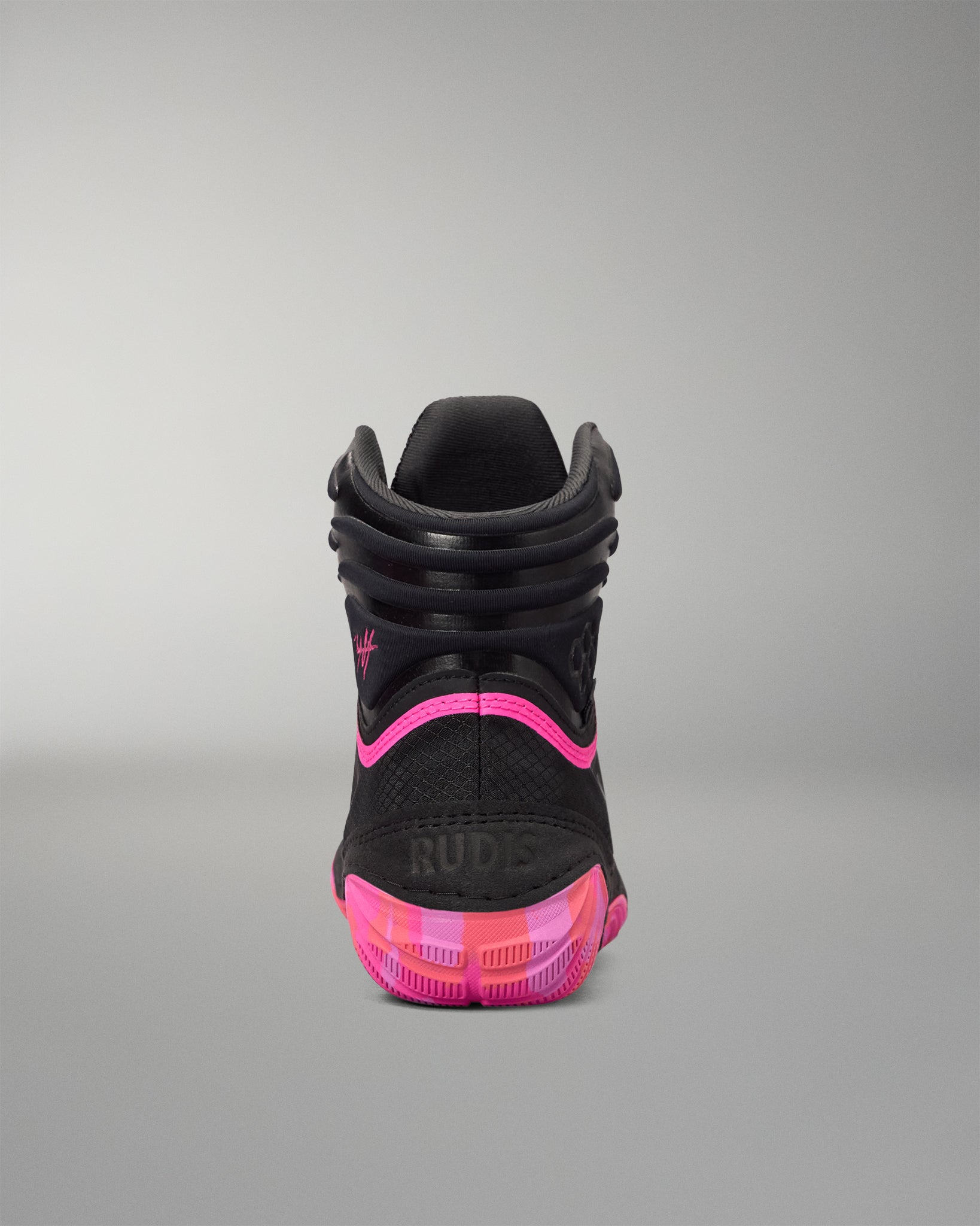 A high-top black wrestling shoe shown from the rear, featuring vibrant hot pink accents on the midsole, outsole, and heel logo, with 'RUDE' printed on the back.