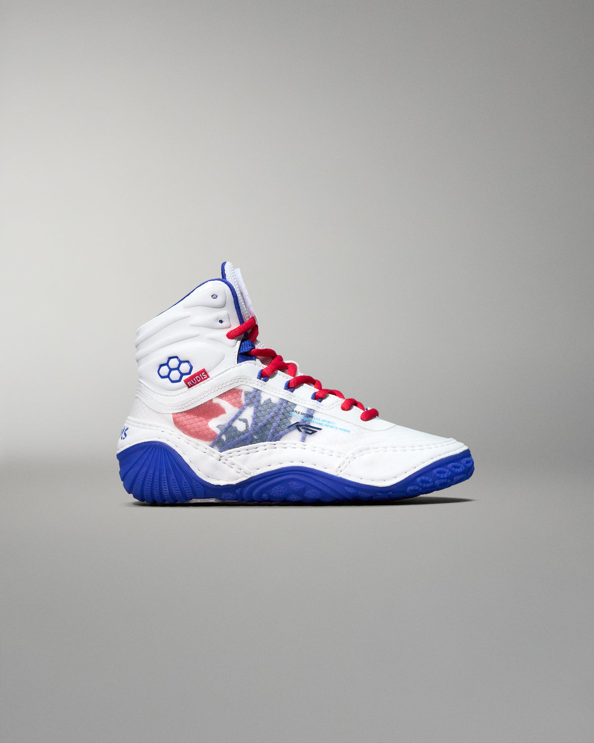 Side view of a white RUDIS KS Infinity Edge Wrestling Shoe featuring a red, white, and blue USA flag-inspired design, red laces, blue outsole, RUDIS hexagon logo near the ankle, and official USA Wrestling branding