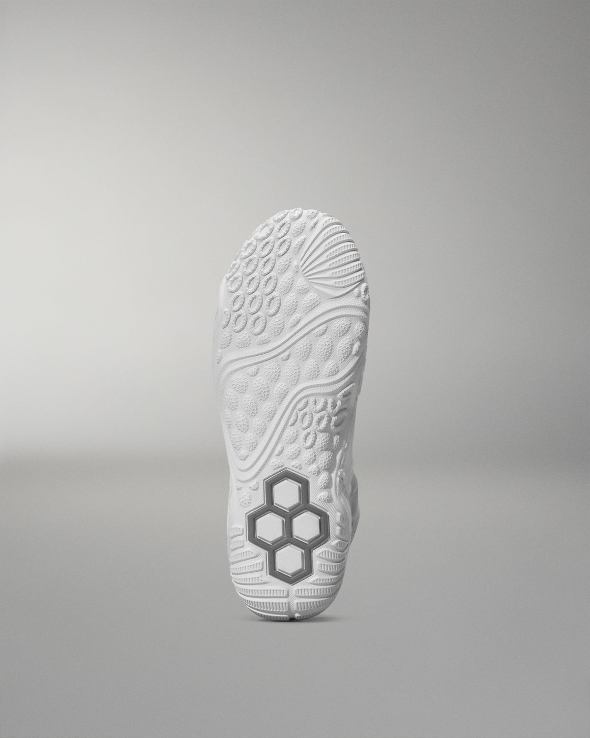 White wrestling shoe sole with a textured pattern and hexagonal logo on a gray background