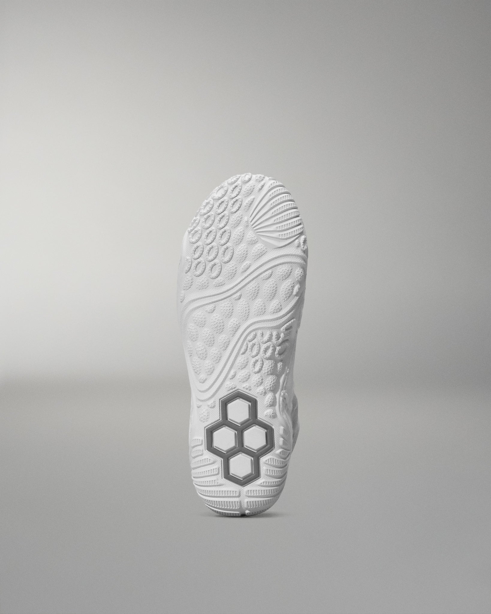 White wrestling shoe sole with a textured pattern and hexagonal logo on a gray background