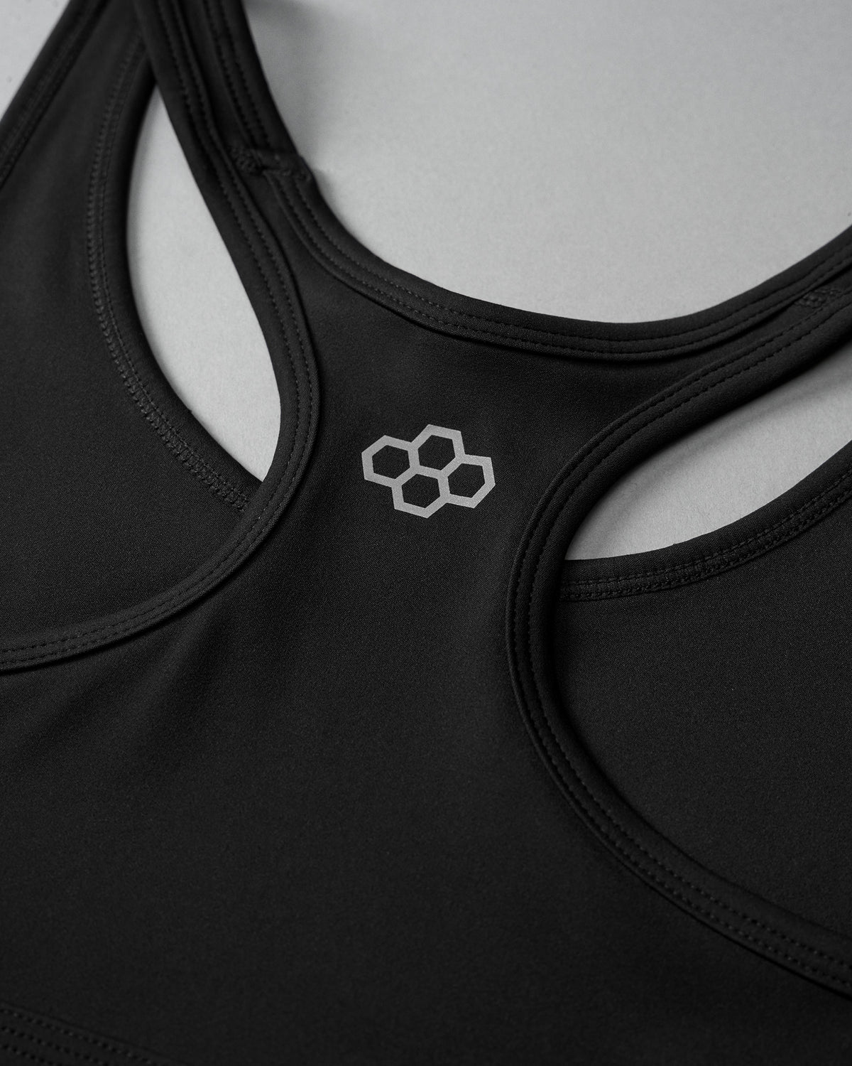 Black sports bra with a geometric logo on a white background