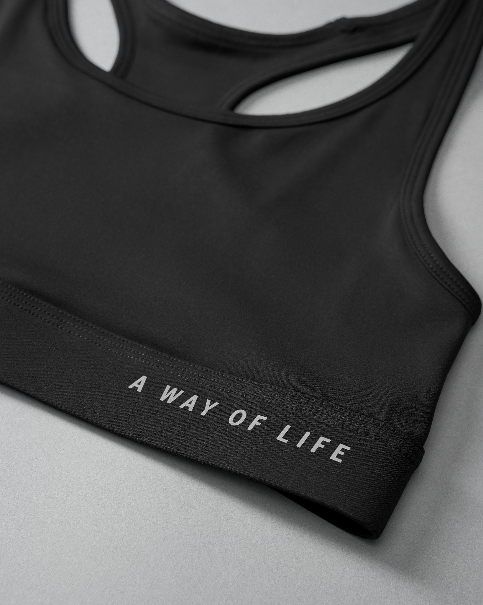 Black sports bra with 'A Way of Life' text on a gray background